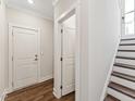 Bright hallway featuring hardwood floors, white doors, trim, and stairs leading to the upper level at 11549 Helmond Way # 103, Raleigh, NC 27617
