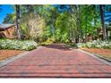 A long brick driveway winds through a verdant, tree-lined neighborhood at 12 Innisfree Dr, Durham, NC 27707