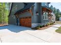The long driveway leads to a wooden garage door on this gray farmhouse style home with stone accents at 1222 Red Cedar Ct, Youngsville, NC 27596