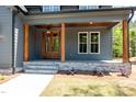 Inviting covered front porch with stone steps, wood columns, stained wood ceiling, and double entry doors at 1222 Red Cedar Ct, Youngsville, NC 27596