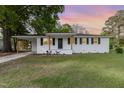 Attractive white brick home featuring a carport, contrasting black shutters, and a lush green lawn at 124 Strickland Dr, Smithfield, NC 27577