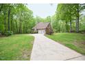 Long driveway leading to a brick home with a two-car garage surrounded by lush greenery at 14 Whit Ct, Angier, NC 27501