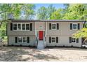 Charming home featuring a bright red front door, black shutters and surrounded by mature trees at 1514 Goodwin Rd, Durham, NC 27712