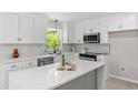 Modern kitchen features white cabinets, stainless appliances, backsplash, quartz countertop, and a lovely window view at 1514 Goodwin Rd, Durham, NC 27712