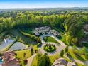 Expansive estate aerial showcasing manicured grounds, a circular driveway, a pond, and mature trees at 16 Portofino Pl, Durham, NC 27707