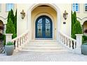 Elegant front entrance with arched doorway, wrought iron doors, and stone steps with potted plants at 16 Portofino Pl, Durham, NC 27707