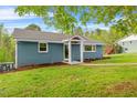 Cozy blue brick home featuring a well-kept lawn, lush landscaping, a covered entry, and a serene outdoor setting at 1751 Riverside Dr, Hillsborough, NC 27278