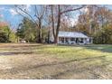 Cozy one-story house with a full-width porch and metal roof, situated on a large lot with mature trees at 1835 Pearidge Rd, Angier, NC 27501
