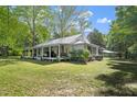 Side view of a quaint one-story house with a metal roof and covered porch, surrounded by trees at 1835 Pearidge Rd, Angier, NC 27501