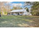 Quaint one-story house with a full-length porch, featuring a metal roof and a generous yard with trees at 1835 Pearidge Rd, Angier, NC 27501