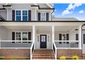 Close-up of a home's front porch with black door, white columns, brick stairs and black railings at 186 Gumtop Dr, Zebulon, NC 27597