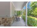 Inviting front porch with stone accents, classic rocking chairs, and lush greenery at 205 Sacred Fire Rd, Louisburg, NC 27549
