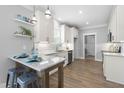 Modern white kitchen with granite countertops, stainless steel appliances, tiled backsplash, and wood flooring at 238 W Paige Wynd Dr, Angier, NC 27501