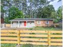 Inviting home with front porch, red door, solar panels and wooden fence, all framed by lush greenery at 2506 N Duke St, Durham, NC 27704