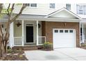 Inviting townhouse exterior with a white garage door, brick accents, and a charming covered porch at 6022 Four Townes Lane Ln, Raleigh, NC 27616