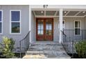 Close-up of the front entrance, featuring a wooden double door, stone steps, and a black metal railing at 67 Farmstead Ct, Wendell, NC 27591