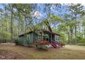 Charming cottage-style home with green siding and red trim nestled among lush trees and landscaping at 952 Glover Rd, Dunn, NC 28334