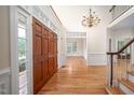 Spacious foyer with hardwood floors, statement chandelier, double doors and bright natural light from above at 10 Twinleaf Pl, Durham, NC 27705