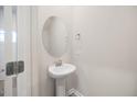 Half bath featuring a pedestal sink, oval mirror, and brushed nickel fixtures at 1048 Winding Spring Dr, Mebane, NC 27302