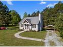 Beautiful single-story house with a metal roof, gray siding, and covered parking surrounded by lush greenery under a blue sky at 108 Ruff Davis Rd, Roxboro, NC 27574