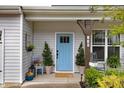 Welcoming front porch with a blue door, decorative plants, and cozy seating area at 130 Stromness Path, Clayton, NC 27527