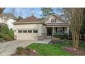 Charming home exterior features a manicured lawn, stone accents, a two car garage, and a cozy front porch at 1320 Heritage Hills Way, Wake Forest, NC 27587