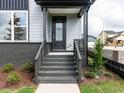 Inviting front porch with gray brick steps, sleek railings, and a modern black front door at 14 Relaxing Way, Pittsboro, NC 27312