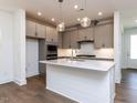Modern kitchen with gray cabinets, stainless appliances, island and wood floors at 14 Relaxing Way, Pittsboro, NC 27312