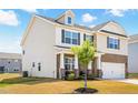 Charming two-story home featuring a brick facade, attached garage, and manicured front yard with a young tree at 1427 Carisbrooke Dr, Mebane, NC 27302