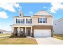 Inviting two-story home featuring brick and vinyl siding, an attached two-car garage, and a cozy front porch at 1427 Carisbrooke Dr, Mebane, NC 27302
