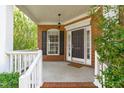 Inviting covered front porch with brick accents, a hanging light fixture, and a decorative welcome mat at 2412 Castleburg Dr, Apex, NC 27523