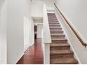 Hallway with hardwood floors leading to carpeted stairs and a view of the kitchen at 3513 Diamond Springs Dr, Raleigh, NC 27610
