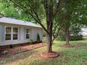 Side yard of a home featuring manicured garden beds and mature trees at 4172 Copeland Ter, Graham, NC 27253