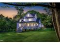 White farmhouse with covered porch and chairs, set against a beautiful sunset and green lawn at 1023 Laura Johnson Rd, Pittsboro, NC 27312