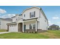 Side view of a charming two-story home with a white facade, brick accents, and a spacious two-car garage at 1121 Landen Creek Ln, Zebulon, NC 27597