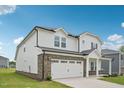 Rear view of a charming two-story home with a white facade, brick accents, and a spacious two-car garage at 1121 Landen Creek Ln, Zebulon, NC 27597