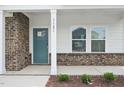 Close up view of the front porch with a teal door, brick accents, and white columns at 1121 Landen Creek Ln, Zebulon, NC 27597