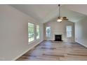 Bright living room featuring a vaulted ceiling, a cozy fireplace, and hardwood floors, enhanced by natural light from large windows at 113 Union Mills Way, Cary, NC 27519