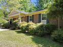 Brick home featuring dark shutters, lovely landscaping, and a covered entryway, providing a welcoming and classic facade at 1616 Beechwood Dr, Raleigh, NC 27609