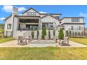 Beautiful backyard with stone patio, fire pit, outdoor seating, and covered deck on a modern white brick home at 1633 Estate Valley Ln, Raleigh, NC 27613