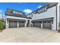 Expansive concrete driveway leading to multiple car garages in a modern home with black trim and white brick at 1633 Estate Valley Ln, Raleigh, NC 27613