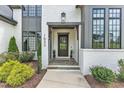 Elegant front entrance featuring a glass-paneled door, stone steps, and stylish landscaping for a welcoming appeal at 1633 Estate Valley Ln, Raleigh, NC 27613