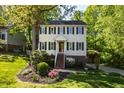 Two-story house with a light yellow exterior, black shutters, brick foundation and lush landscaping at 213 Beechtree Dr, Cary, NC 27513