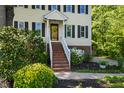 Inviting front entrance with brick stairs, white railings, landscaped garden bed, and yellow siding at 213 Beechtree Dr, Cary, NC 27513