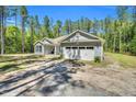 View of home's garage, gravel driveway, and well-manicured lawn surrounded by a natural wooded area at 2784 Norrington Rd, Lillington, NC 27546