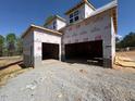 Spacious, unfinished three-car garage with concrete block foundation under construction with blue sky background at 348 Inspiration Way, Fuquay Varina, NC 27526
