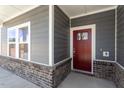 Close-up of a modern home's entrance, highlighting the stylish red door and brick detailing at 3715 Rosebush Dr, Zebulon, NC 27597