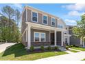 A beautifully designed home featuring a covered front porch and complemented by lush greenery and trees at 3715 Rosebush Dr, Zebulon, NC 27597