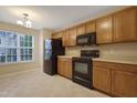 Well-lit kitchen featuring wooden cabinets, black appliances, and a window overlooking the yard at 5329 Big Bass Dr, Raleigh, NC 27610