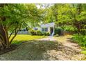 Charming single-story home with blue shutters, green lawn and mature shade trees at 705 Hartford Rd, Raleigh, NC 27610